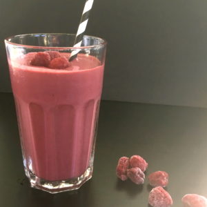 raspberry chocolate smoothie in a glass with a straw